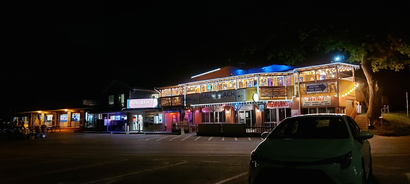 A few commercial buildings, lit by yellow streetlights and colourful string lights, its tacky and beautiful